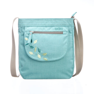 Light blue crossbody bag with floral embroidery and 'Haiku' branding on a white background