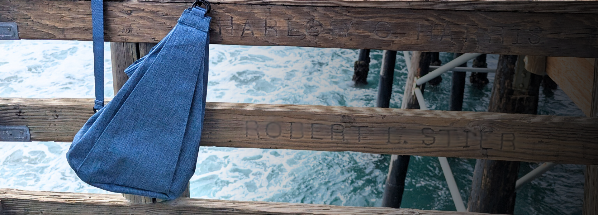 Blue bag hanging on a wooden pier with water in the background
