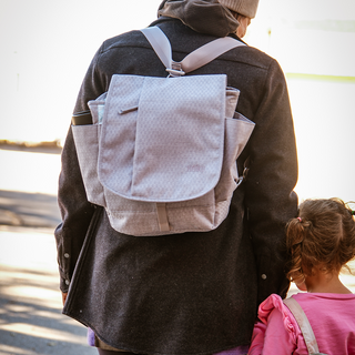 Person with a gray backpack and child in pink jacket outdoors