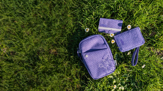 Vineyard Violet Sprout Wallet, RFID Mini Wallet, and Endeavor Pouch on a grass background