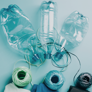 Recycled plastic bottles repurposed as light bulbs with yarn on a blue background